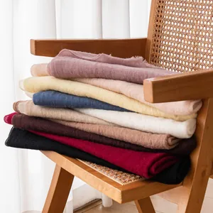Soft solid color cashmere scarves stacked on a chair for spring and autumn style