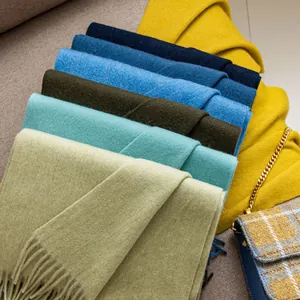 Close-up detail of multiple soft solid-colored wool scarves with elegant tassel fringe