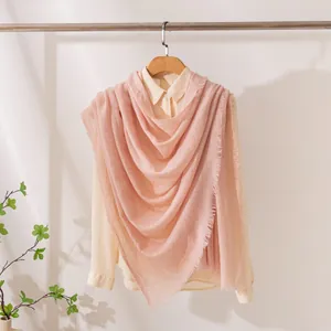 Elegante scialle lungo in misto lana rosa tenue drappeggiato su una camicia di moda.
