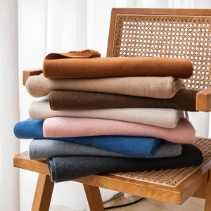 Stack of soft colorful wool blend scarves with fringe tassels displayed on a wooden chair