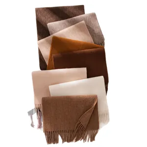Stack of soft wool scarves in various earthy tones with elegant tassel fringe details for winter