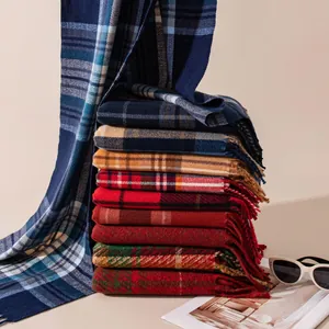 Detailed view of stacked cozy checkered winter scarves with tassels in various autumn colors