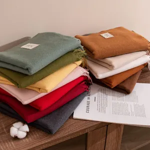 Solid color imitated cashmere scarves in Morandi palette stacked on a wooden table
