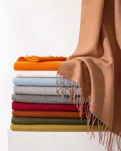 Detailaufnahme eines Stapels weicher, bunter einfarbiger Winterschals mit Quasten
