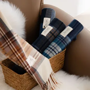 Collection of assorted plaid scarves with tassels in a woven basket for cozy winter warmth.