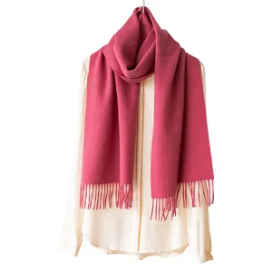 Eleganter weicher rosafarbener Wollschal mit langen Fransen an einer weißen Bluse für den Winter