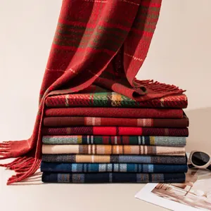 Folded stack of colorful Christmas plaid scarves with fringe tassels in various patterns
