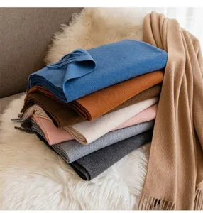 Close-up of a colorful stack of soft wool scarves with tassels in various winter shades.