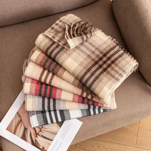 Cozy plaid imitation cashmere scarves stacked on a warm brown sofa chair