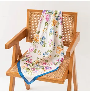 Close-up detail of an elegant floral print silk scarf draped on a vintage rattan chair