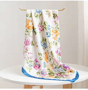 Detail view of a white floral silk scarf draped elegantly over a gold display stand.