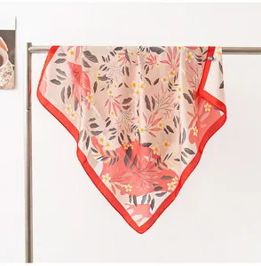 Detailed view of floral silk scarf with elegant red border hanging on a rack