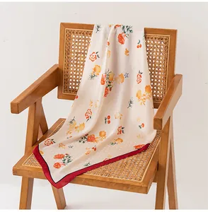 Elegante sciarpa in finta seta con stampa floreale drappeggiata su sedia in rattan