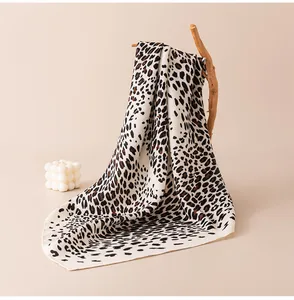 Dettaglio ravvicinato di un foulard di seta con stampa leopardata su un ramo di legno