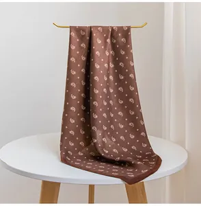 Détail en gros plan d'un foulard en soie marron vintage drapé sur un support doré chic