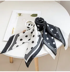 Detail shot of black and white polka dot silk scarves on a white table.