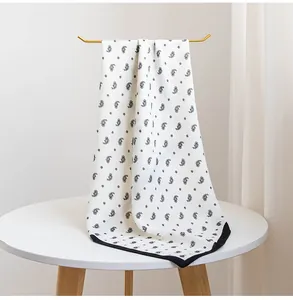 Gros plan du motif paisley sur un foulard en soie carré blanc avec bordure noire