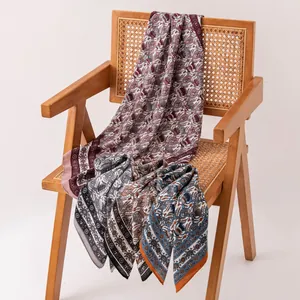 Détail de divers foulards en soie vintage drapés élégamment sur une chaise en rotin