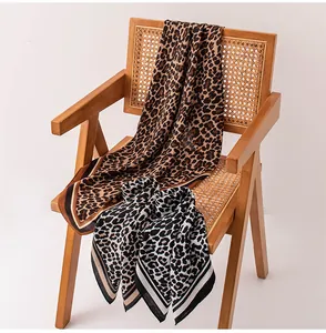 Eleganti sciarpe di seta con stampa leopardata adagiate su una sedia di legno vintage.