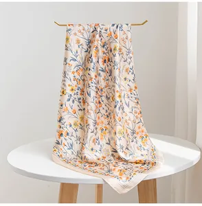 Elegante sciarpa di seta con stampa floreale drappeggiata su un supporto dorato su un tavolo