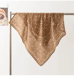 Détail d'un foulard en soie marron avec motifs paisley et fleurs sur un support