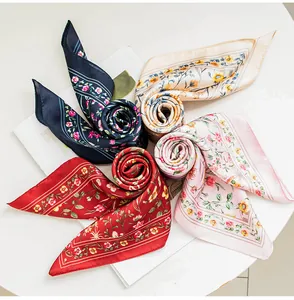 Dettaglio di quattro sciarpe in seta sintetica con stampa floreale a forma di rosa.