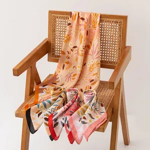 Elegant floral print silk-like neck scarves draped over a vintage wooden rattan chair