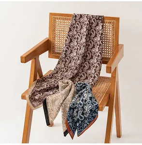 Détail de foulards en soie cachemire rétro marron et bleu sur une chaise en rotin.