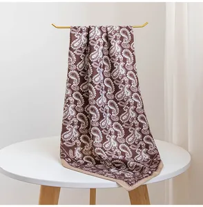 Détail d'un foulard en soie marron vintage avec motif paisley et bordure beige