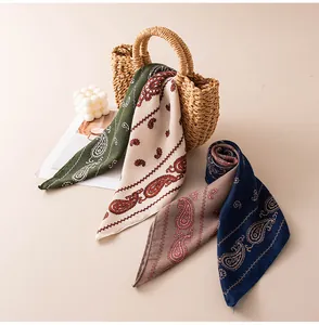 Gros plan de foulards carrés vintage à motifs cachemire drapés sur un sac en paille.