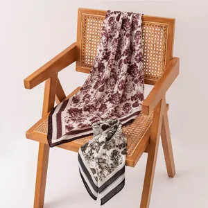 Vue détaillée de deux foulards en soie à fleurs vintage sur une chaise en rotin.
