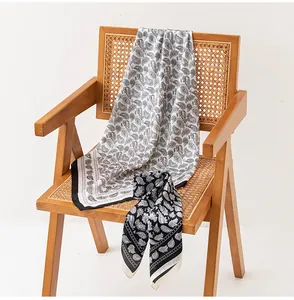 Elegante sciarpa in simil seta con stampa paisley drappeggiata su una sedia