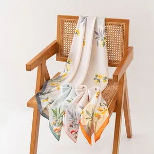 Eleganti foulard in finta seta con stampa floreale su sedia in rattan per donna