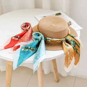 Elegante zijden sjaal met bloemenprint en strohoed op een minimalistische tafel