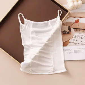Macro detail view of a white ruched silk-like spaghetti strap camisole on a tray