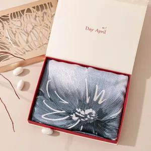 Elegante sciarpa di seta blu con motivi floreali bianchi in una confezione regalo di lusso