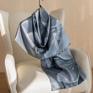 Dettaglio di una sciarpa di seta blu di lusso con motivo floreale su una sedia bianca