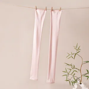Detailed view of light pink mulberry silk sun protection arm sleeves hanging naturally.
