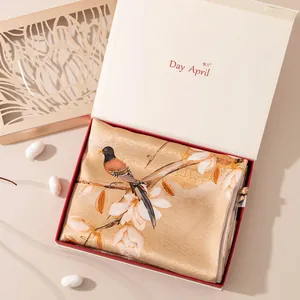 Detail of premium silk scarf with bird and floral pattern in elegant gift box packaging