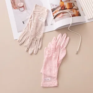 Detailansicht eleganter Spitzenhandschuhe aus Seide in Rosa und Beige auf neutralem Grund