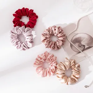 Gedetailleerd overzicht van elegante zijden scrunchies in diverse kleuren met parelketting