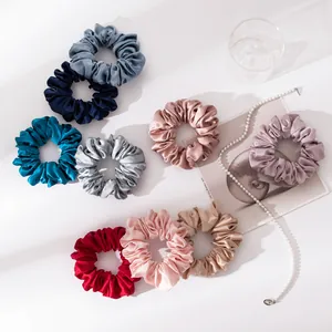 Gedetailleerd bovenaanzicht van negen kleurrijke zijden scrunchies met glanzende textuur