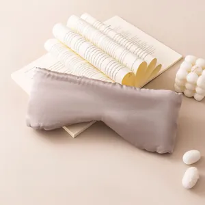 Close-up view of a premium oversized silk sleep eye mask placed on vintage book pages