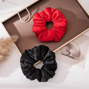 Close-up of elegant red and black silk satin large scrunchies on a decorative tray