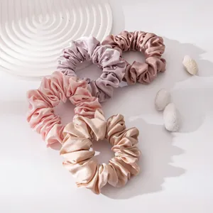 Detail van vier elegante zijden scrunchies in zachte pastelkleuren