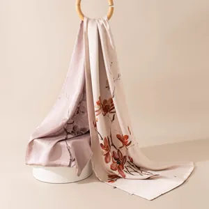 Détail d'une écharpe en soie de mûrier avec motif floral et anneau en bois