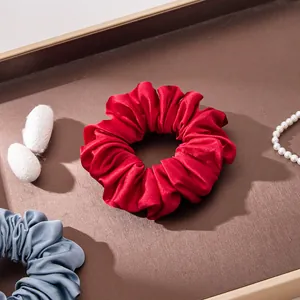 Close-up van rode moerbeizijde scrunchie op een bruin dienblad met zijdecocons