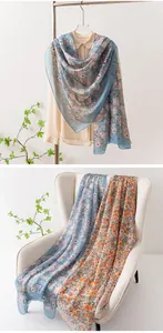 Élégante écharpe en mousseline à fleurs drapée sur une chaise blanche et cintre.