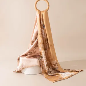 Elegant silk scarf detail with floral patterns and birds draped on a wooden ring