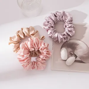 Detailopname van drie zijden scrunchies in champagne roze en lila zijdeachtige kleuren